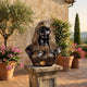 Classical Egyptian Queen Bust by Giant Sculptures in black and gold bronze on a stone pedestal, set on a Tuscan terrace with potted flowers and olive trees.