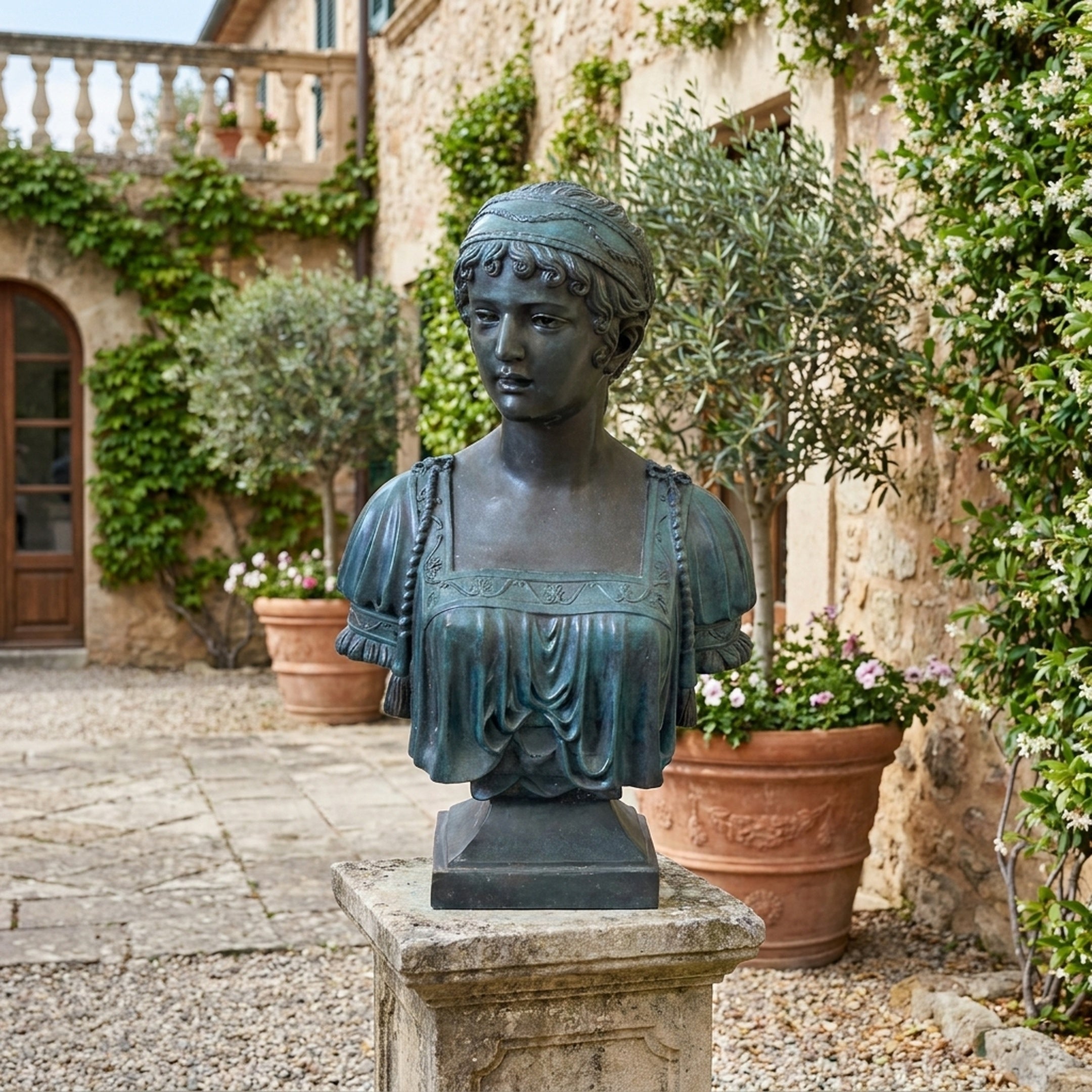 Classical Female Bust Bronze Bust 70cm by Giant Sculptures, verdigris-patinated bronze with draped gown and headband, on a stone plinth in a Mediterranean courtyard.