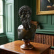 Classical Male Bust Bronze Sculpture by Giant Sculptures, 70cm, on a turned wooden pedestal atop a wooden cabinet in a green-panelled library.