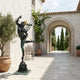 Classical Mercury God of Speed Bronze Sculpture by Giant Sculptures with gilded helmet and caduceus, displayed on a Mediterranean terrace beside an archway.