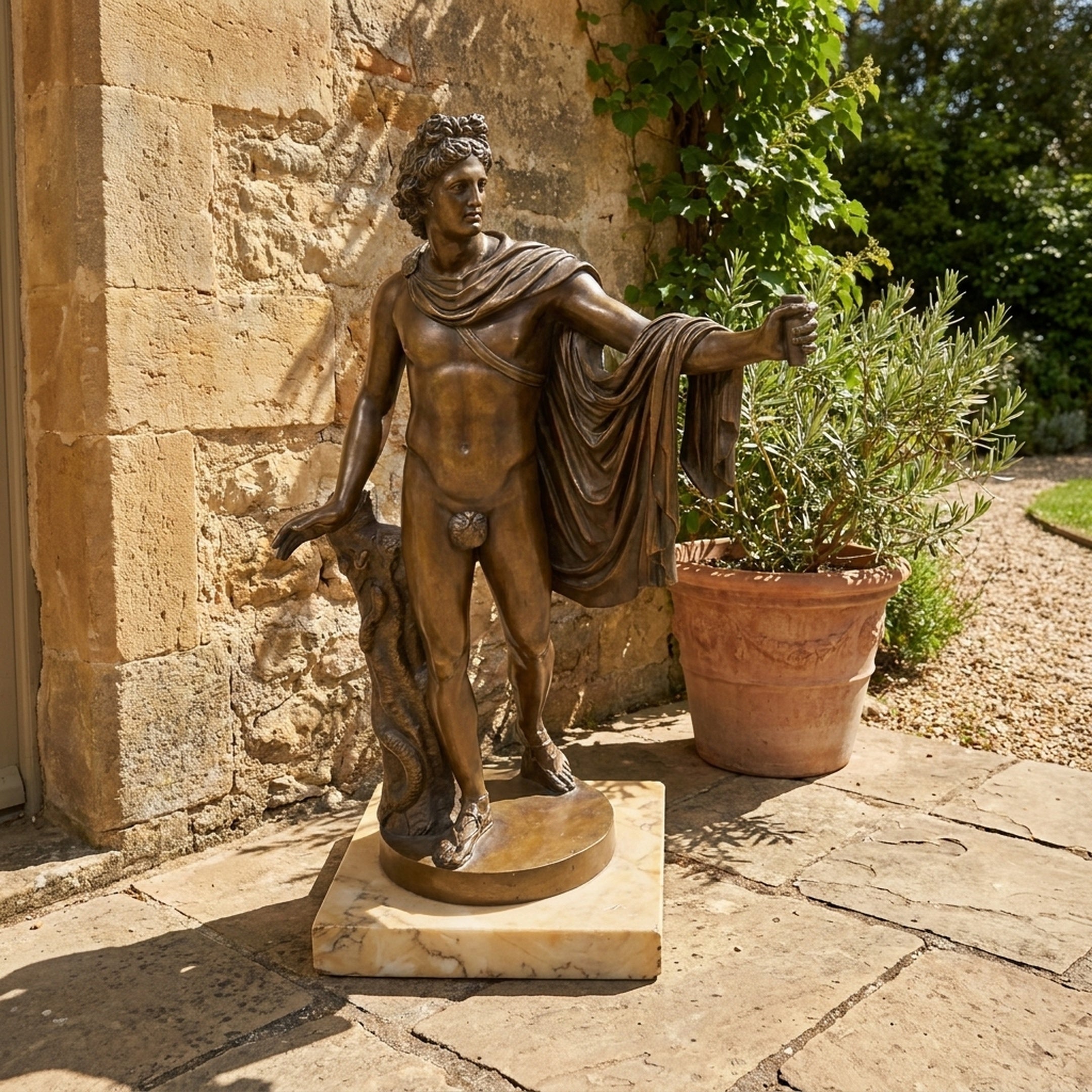 Classical Nude Male Figure Bronze Sculpture by Giant Sculptures in contrapposto pose with draped cloak on a marble base, displayed on a stone patio.