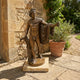 Classical Nude Male Figure Bronze Sculpture by Giant Sculptures in contrapposto pose with draped cloak on a marble base, displayed on a stone patio.