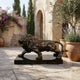 Classical Prowling Lion Bronze Sculpture by Giant Sculptures on a black marble base, displayed on a Mediterranean stone courtyard beside potted olive and lavender.
