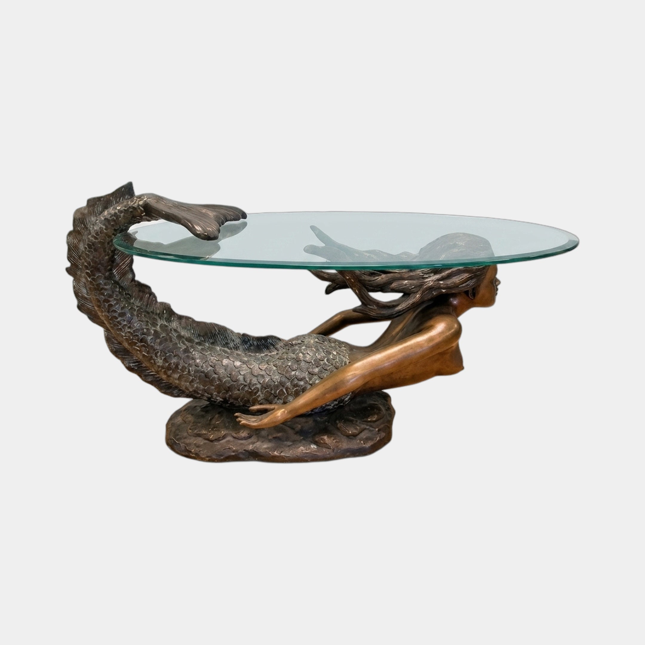 Classical Reclining Mermaid Bronze Table Sculpture by Giant Sculptures, with antiqued tail arched up to support an oval glass top, on a plain background.