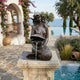 Classical Seated Mermaid Bronze Fountain by Giant Sculptures, 90cm, shown on a stone pedestal beside a pool with sea views and bougainvillea.