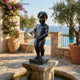 Classical Urinating Boy Bronze Fountain by Giant Sculptures, 130cm dark patinated bronze figure on a stone pedestal beside a poolside terrace overlooking the sea.