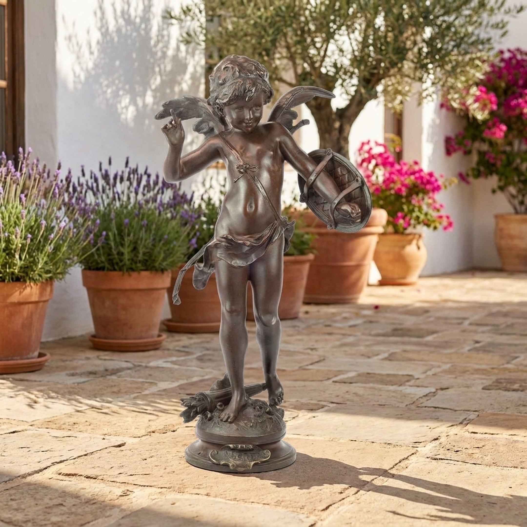 Giant Sculptures' 120cm Classical Winged Cherub Bronze Sculpture with raised arm and hanging basket, displayed on a stone courtyard beside lavender and terracotta pots.