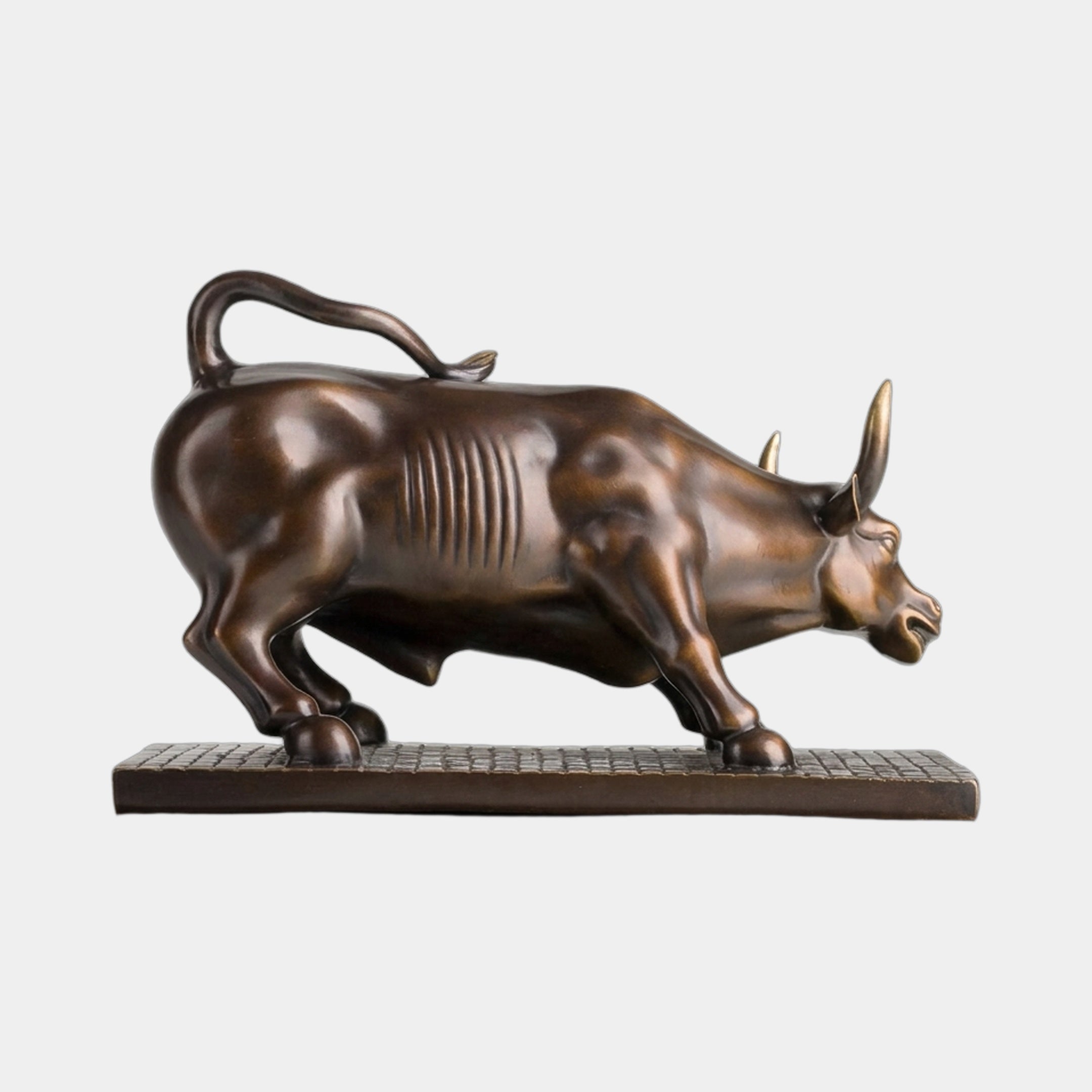 Contemporary Charging Bull Bronze Sculpture by Giant Sculptures shown in side profile with dark brown patina, polished gold horns, and cobblestone base.