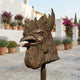 Contemporary Crowing Rooster Head Bronze Sculpture by Giant Sculptures, shown in profile on a sunlit terrace with potted lavender and bougainvillea.