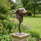 Contemporary Dog Head Bronze Sculpture by Giant Sculptures, 45cm bust with warm brown patina on a textured stem, displayed on a stone plinth in a garden.