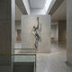 Contemporary Emerging Male Figure Bronze Relief by Giant Sculptures, 110cm muscular torso bursting from a concrete panel with arm raised, in a minimal gallery.