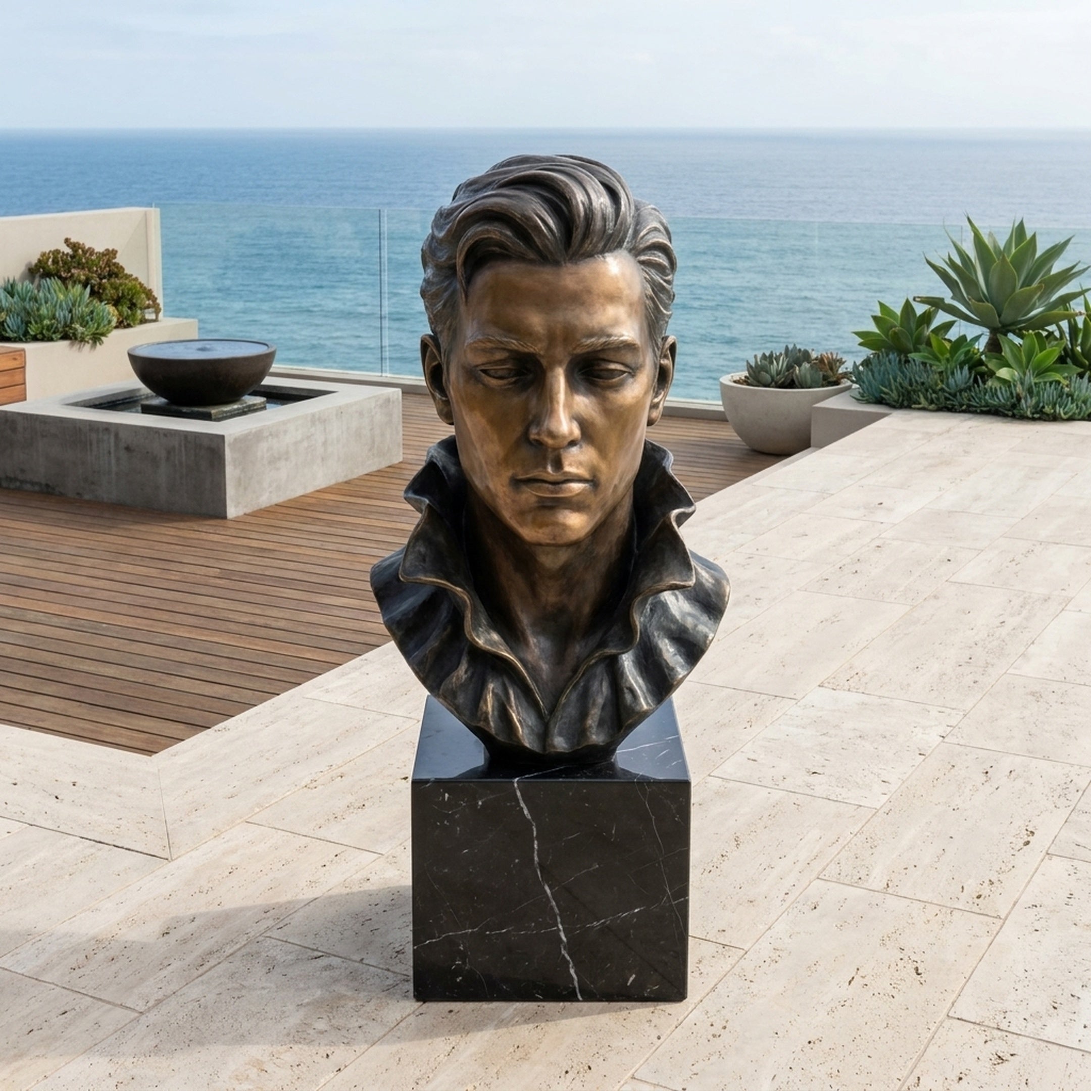 Contemporary Male Bust Bronze Bust 100cm by Giant Sculptures on a black marble plinth, shown on an oceanfront terrace with succulents and a water feature.