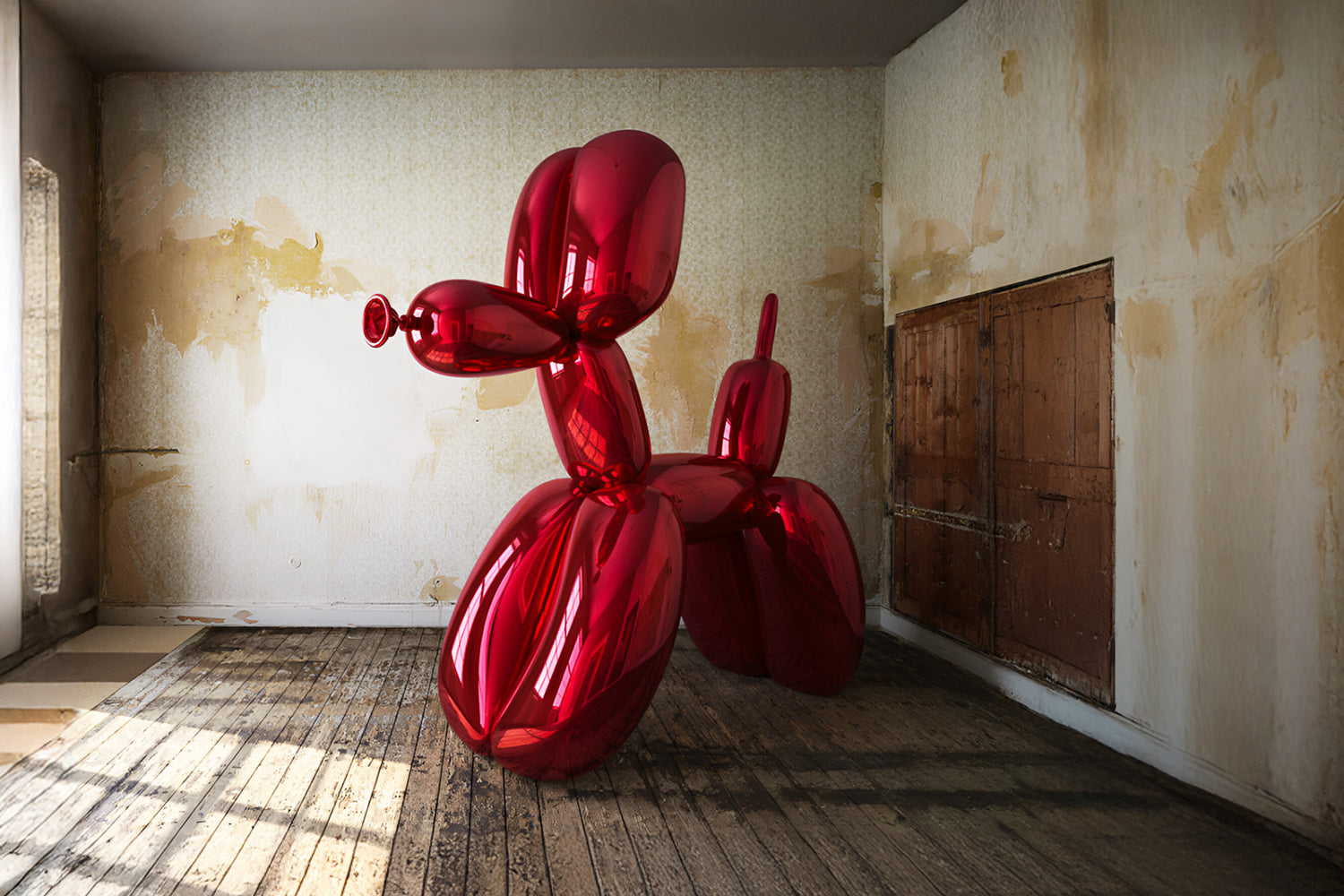 A large, shiny red balloon sculpture shaped like a dog stands in a worn, rustic room with peeling wallpaper and wooden floors. The room has an open closet door revealing a dark interior.