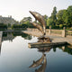 Giant Sculptures Contemporary Leaping Dolphins Bronze Sculpture in warm brown patina beside a reflecting pool on a balustraded terrace before a manor house.