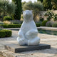 Giant Contemporary Polar Bear Bronze Sculpture by Giant Sculptures in glossy white, seated upright on a black plinth beside a garden pool with lavender.