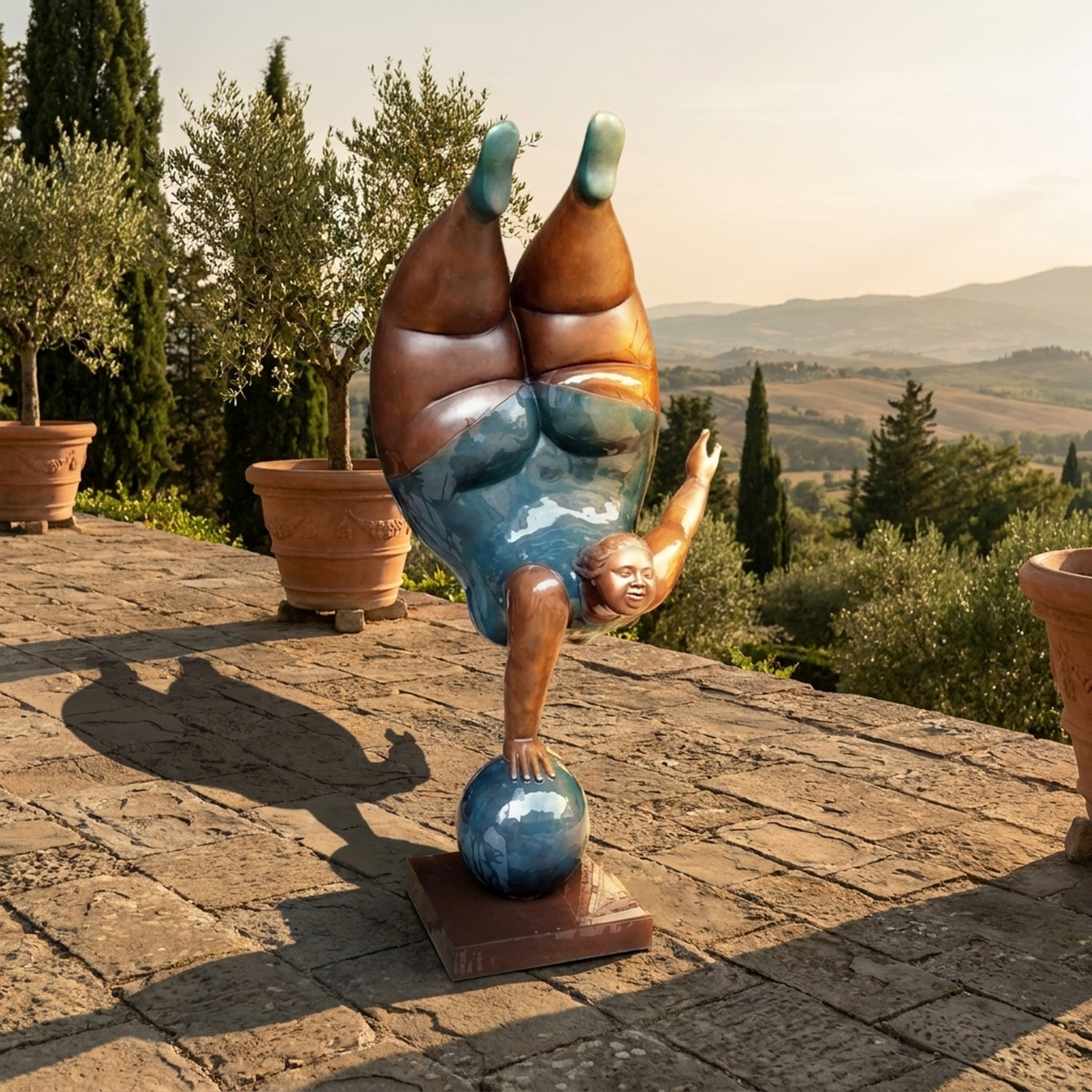 Giant Sculptures Contemporary Rotund Figure Handstand Bronze Sculpture balancing on a polished teal sphere, displayed on a Tuscan stone terrace at sunset.