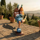 Giant Sculptures Contemporary Rotund Figure Handstand Bronze Sculpture balancing on a polished teal sphere, displayed on a Tuscan stone terrace at sunset.