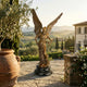 Large Classical Archangel Michael Bronze Sculpture by Giant Sculptures with wings spread and sword, on a dark round plinth overlooking a Tuscan vineyard.