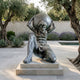 Large Classical Atlas Bearing Globe Bronze Sculpture by Giant Sculptures on a stone plinth in a Mediterranean courtyard with olive trees and lavender.