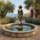 Giant Sculptures Large Classical Boy with Frogs Bronze Fountain 180cm in a round stone basin on a Mediterranean terrace with lavender, olive trees, and sea view.