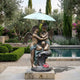 Giant Sculptures' 170cm Large Classical Cherubs Under Parasol Bronze Sculpture on a stone plinth beside a garden pool, framed by olive trees and lavender.