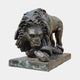 Large Classical Crouching Lion Bronze Sculpture by Giant Sculptures, shown in a forward crouch with paw on a serpent, dark antique patina with verdigris.