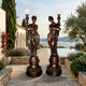 Pair of 240cm Large Classical Goddess Torchère Bronze Sculptures by Giant Sculptures, draped female figures holding frosted globe lamps on tiered plinths beside a poolside terrace.
