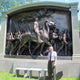 Giant Sculptures Large Classical Mounted Officer and Infantry Bronze Relief at 200cm, with a man standing beside it for scale before the framed processional panel.