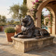 Large Classical Recumbent Roaring Lion Bronze Sculpture by Giant Sculptures on a stone plinth in a Mediterranean courtyard with olive trees and bougainvillea.