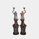 Mirrored pair of Large Classical Winged Figure Torch Lamp Bronze Sculptures by Giant Sculptures, seated robed figures raising frosted flame shades atop fluted columns.