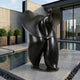 Large Contemporary Abstract Female Figure Bronze Sculpture by Giant Sculptures in black patina, displayed on a paving slab beside a reflecting pool at a modern home.