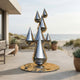 Large Contemporary Abstract Raindrop Cluster Sculpture 250cm by Giant Sculptures in mirror-polished steel on a beachfront patio with bench and potted plants.
