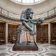 Giant Sculptures' 220cm Contemporary Chimpanzee on Books with Skull bronze, with brown and verdigris patina, displayed in a domed library rotunda lined with bookshelves.