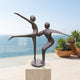 Large Contemporary Dancing Figures Bronze Sculpture by Giant Sculptures on a pale stone plinth, displayed on an oceanview terrace beside potted succulents.