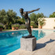 Large Contemporary Diving Athlete Bronze Sculpture by Giant Sculptures, 180cm, on a granite cube plinth beside a poolside garden with lavender and olive trees.