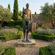 Large Contemporary Fragmented Traveller Bronze Sculpture by Giant Sculptures, 210cm, mid-stride with suitcase on a stone base in a lavender garden path.