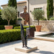 Giant Sculptures' Large Contemporary Fragmented Traveller Figure Bronze Sculpture with warm brown patina, holding a suitcase on a stone base beside a villa courtyard pool.
