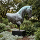 Large Contemporary Horse Head Bronze Sculpture by Giant Sculptures on a black plinth in a garden, showing dark patina with green verdigris and white streaking.