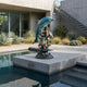 Large Contemporary Leaping Dolphin and Reef Bronze Sculpture by Giant Sculptures displayed on a concrete plinth beside a pool at a modern home.