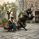 Large Contemporary Reading Bull and Figure Bronze Sculpture by Giant Sculptures, dark bull rearing to read a book beside a golden seated man on a courtyard bench.
