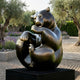 Large Contemporary Seated Bear Bronze Sculpture by Giant Sculptures with dark patina and golden highlights, displayed on a black plinth in a garden with olive trees and lavender.