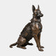 Large Contemporary Seated Military Working Dog Bronze Sculpture by Giant Sculptures, a German Shepherd in tactical vest with dark patina, on plain background.