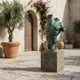 Large Contemporary Twisting Male Torso Bronze Sculpture by Giant Sculptures with green verdigris patina on a stone plinth in a Mediterranean courtyard.