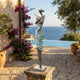 Large Contemporary Violinist Bronze Sculpture by Giant Sculptures on a stone plinth beside an infinity pool with sea views, bougainvillea, and olive trees.