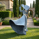 Large Contemporary Wind-Swept Female Figure Bronze Sculpture by Giant Sculptures in weathered grey-blue patina, displayed on a lawn in a Tuscan garden.