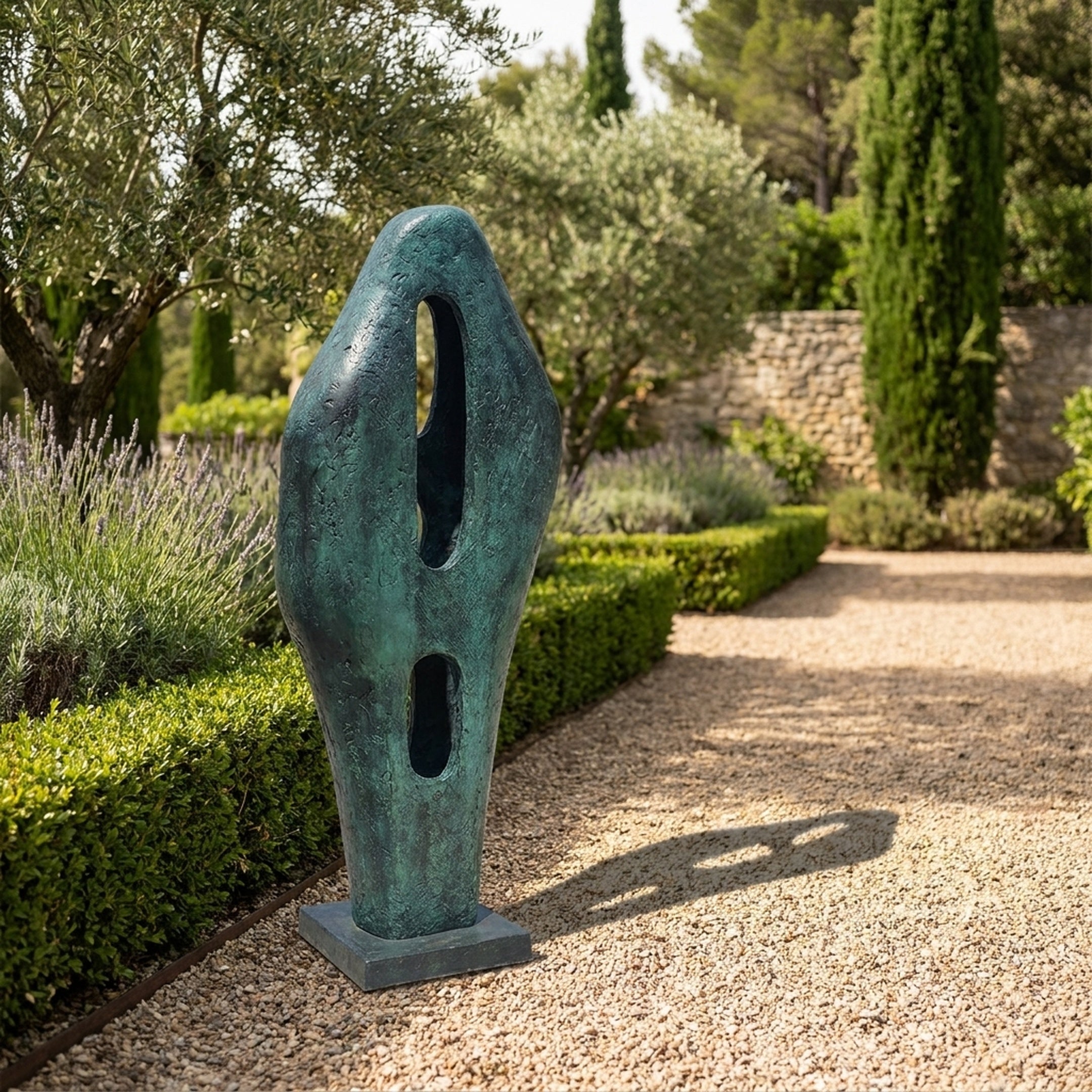 Large Modern Abstract Bronze Sculpture 120cm by Giant Sculptures with verdigris patina and two oval apertures, set on a gravel garden path beside lavender and hedging.