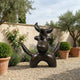 Large Modern Abstract Bull Bronze Sculpture by Giant Sculptures with dark patina, displayed on gravel in a Mediterranean garden with olive trees and roses.