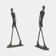 Two views of the Giant Sculptures Large Modern Elongated Walking Male Figure Bronze Sculpture, 200cm, showing the textured dark patina mid-stride on a plain background.