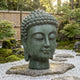 Large Traditional Buddha Head Bronze Bust by Giant Sculptures with verdigris patina, displayed on a stone slab atop white gravel in a Japanese garden.