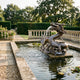 Giant Sculptures Large Traditional Chinese Dragon Bronze Fountain 150cm spouting water in a formal garden pond with stone balustrade and lily pads.